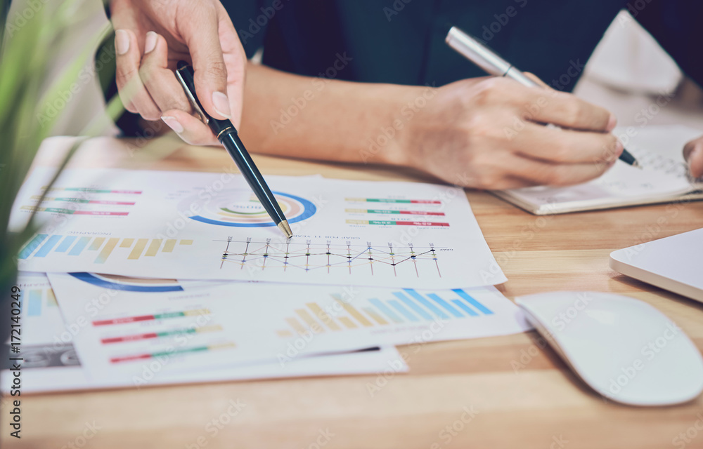 Hand pointing to a financial document on the desk. Between the agreed form of work to send customers. Teamwork ideas work best. Hand pointing to a financial document on the desk. Between the agreed form of work to send customers. Teamwork ideas work best.