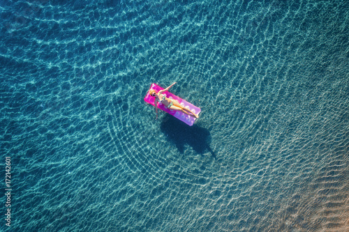 Photography Aerial view of young woman swimming on the pink inflatable mattress in the transparent turquoise sea in Ichmeler,Turkey