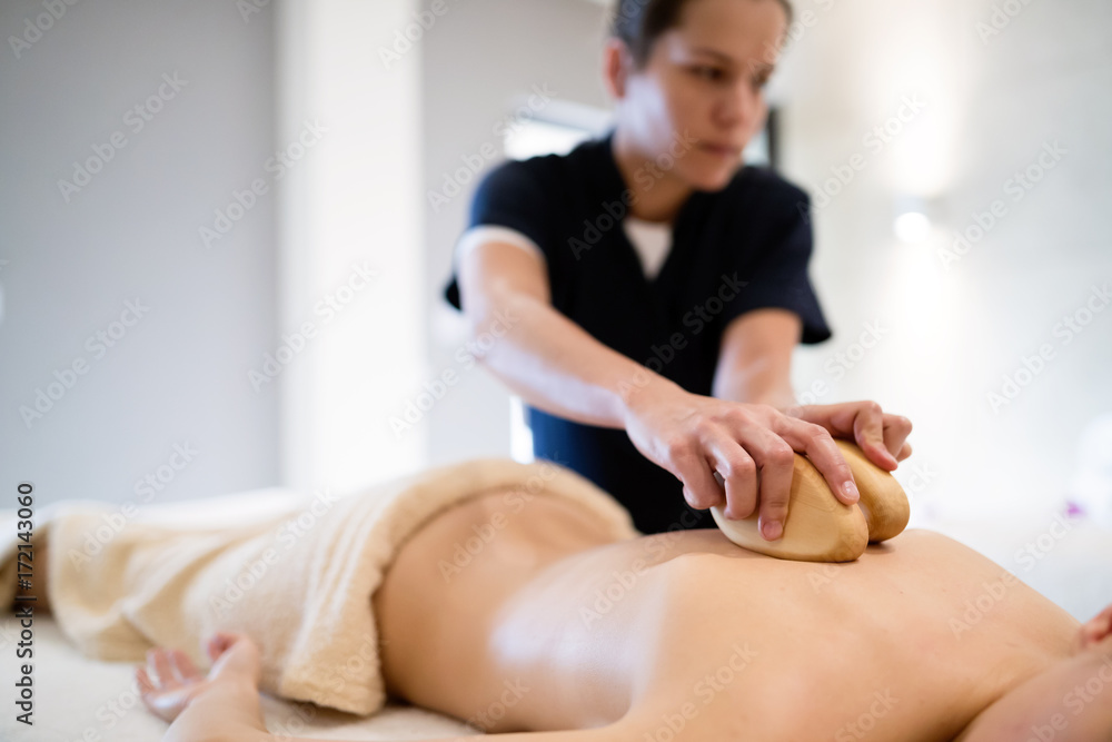 Massage therapist using wooden tool to massage patient Massage therapist using wooden tool to massage patient