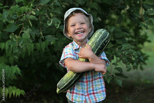 A small laughing emotional boy is busy harvesting. The kid in the plaid shirt is pleased with helping his father work on the farm.