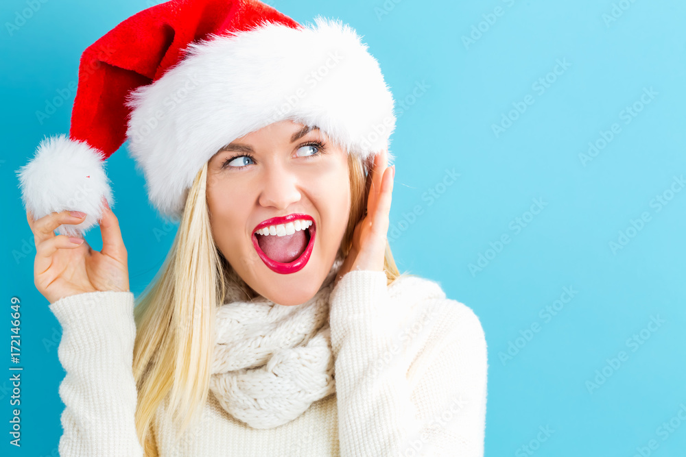 Happy young woman with Santa hat on a blue background Happy young woman with Santa hat on a blue background