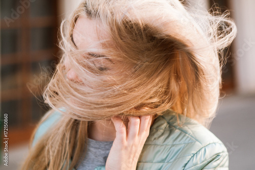 Woman with windy hair in motion closeup. Happy and young independent girl on street