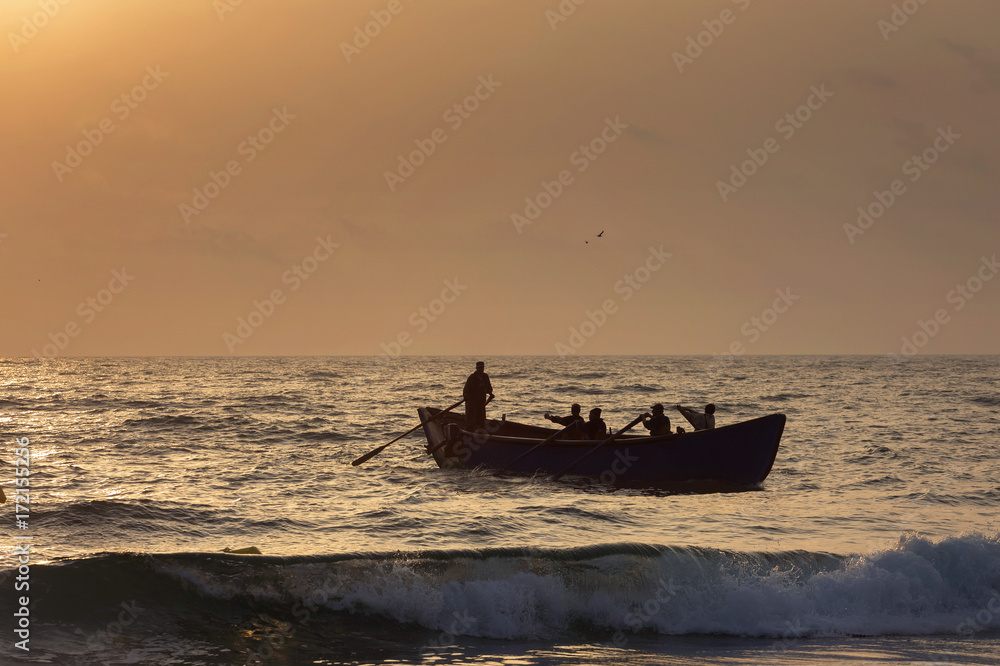 Fishermen silhouettes on boat, at sunrise