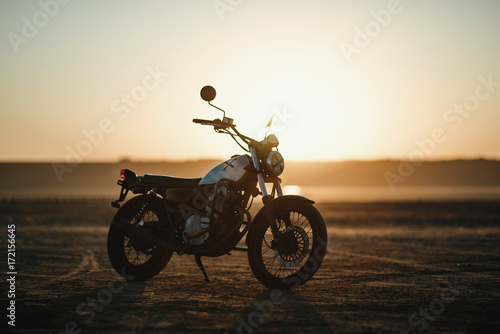  old custom beautiful cafe racer motorcycle in the desert at sunset or sunrise 