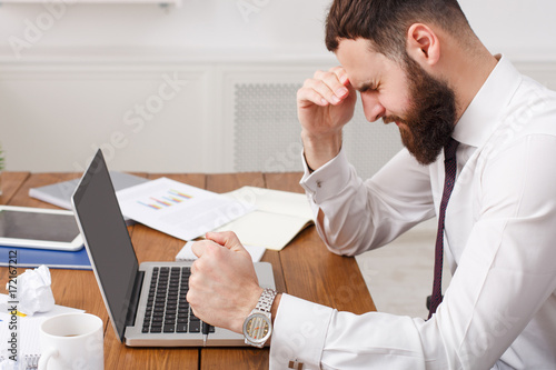 Tired businessman at desk with laptop searching way out from difficult situation. Close up, crop