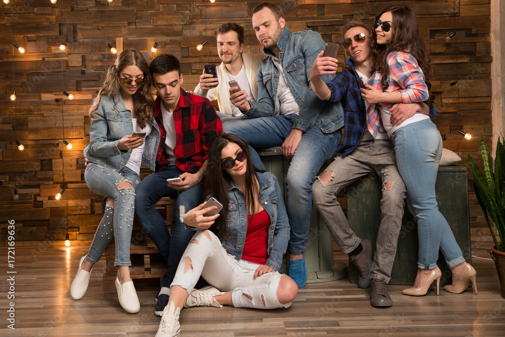Group of  friends happy people, students with smartphones in their hands are watching social networks. Having fun on the Internet online. Positive girls and boys Friendship between men and women.