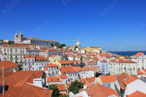 Famous portuguese red roofs in Alfama old town historical district on summer time. Miradouro Portas do Sol viewpoint in Lisbon Portugal. Empty clear blue sky and cityscape architecture background
