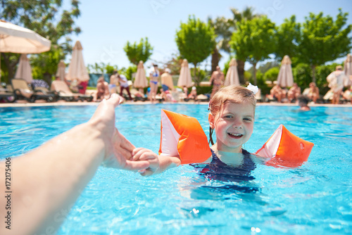 Canvas Print Girl swimming in the pool in armlets on a hot summer day.