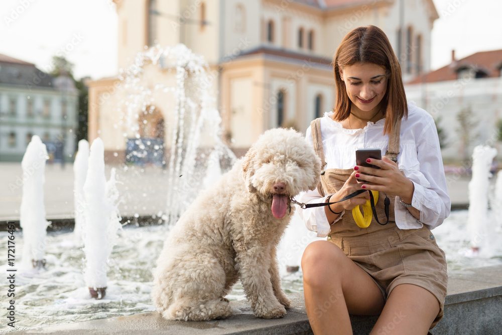 Woman using smart phone and  enjoying summer days with her dog. - obrazy, fototapety, plakaty 