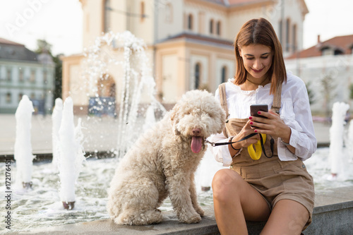 Woman using smart phone and  enjoying summer days with her dog.