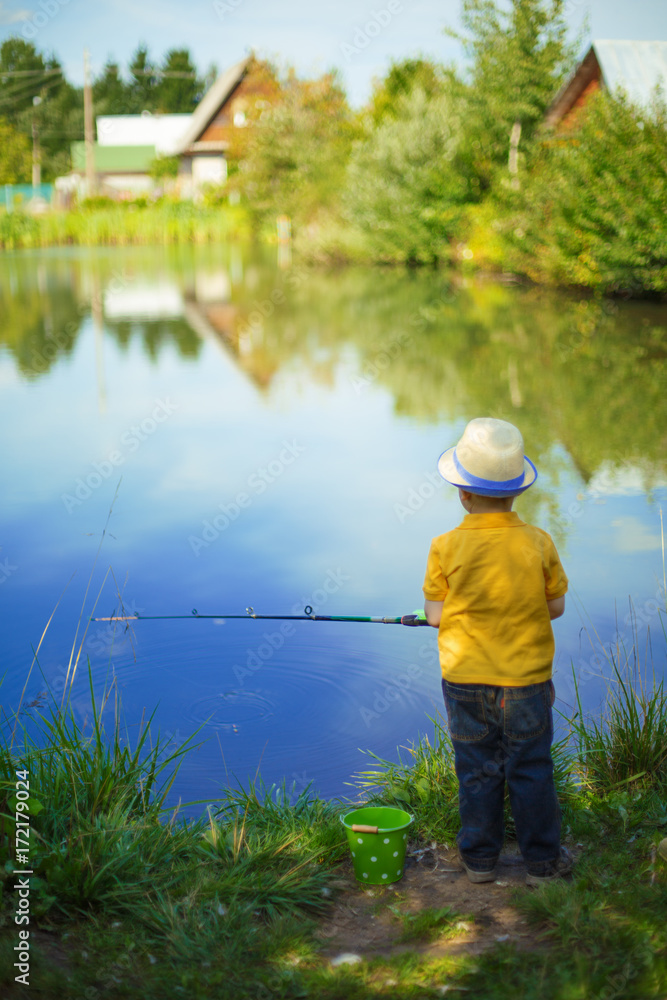 Little boy is engaged in fishing in a pond. Child with a dairy in his hands.
