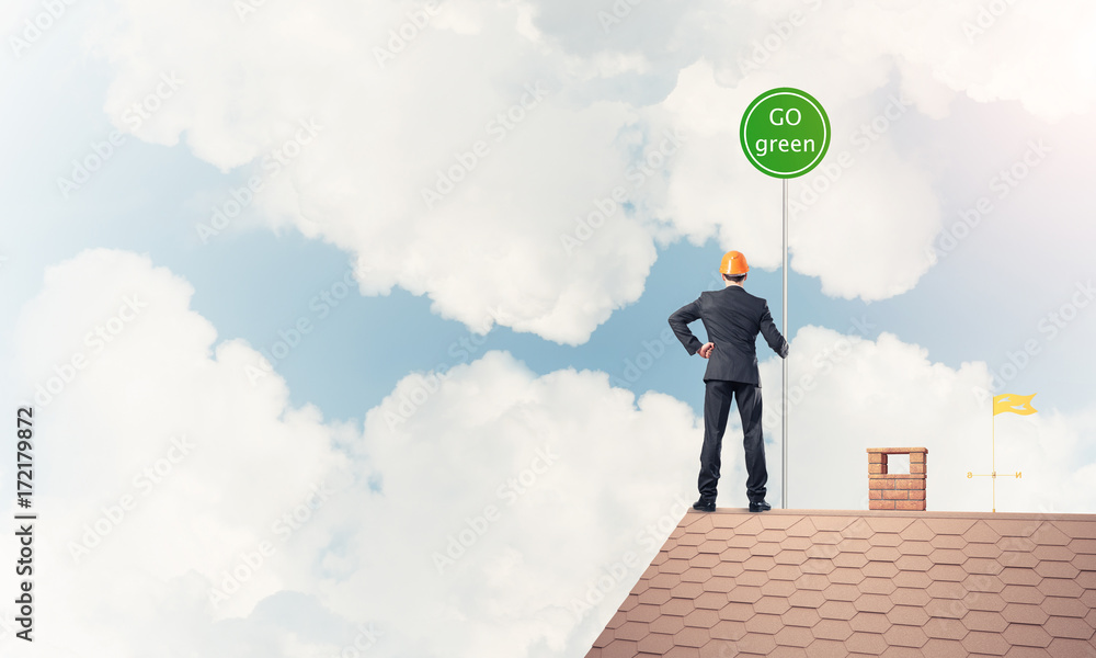Businessman in suit on house top with ecology concept signboard. Businessman in suit on house top with ecology concept signboard.