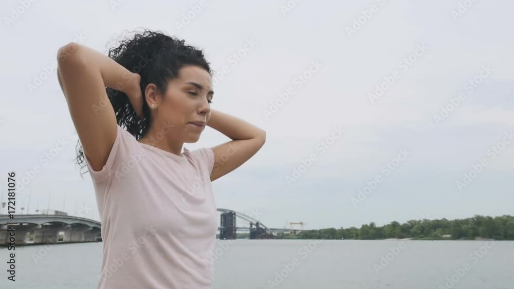 Man with woman on shoulders does a squats near the river