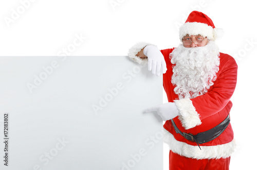 Happy Santa Claus looking out from behind the blank sign isolated on white background © lenets_tan
