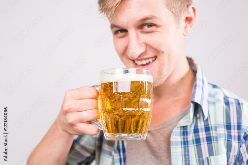 Cheerful young man holding a beer mug full of beer and smiling on white background, close up portrait Cheerful young man holding a beer mug full of beer and smiling on white background, close up portrait