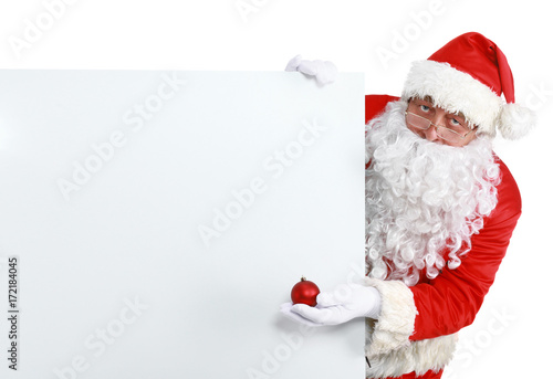Happy Santa Claus looking out from behind the blank sign isolated on white background © lenets_tan