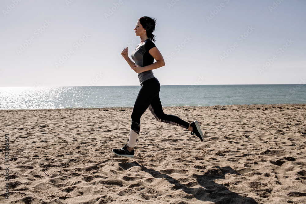 beautiful girl with sports forms sports on the beach, drinking water, jumping, running, doing different exercises