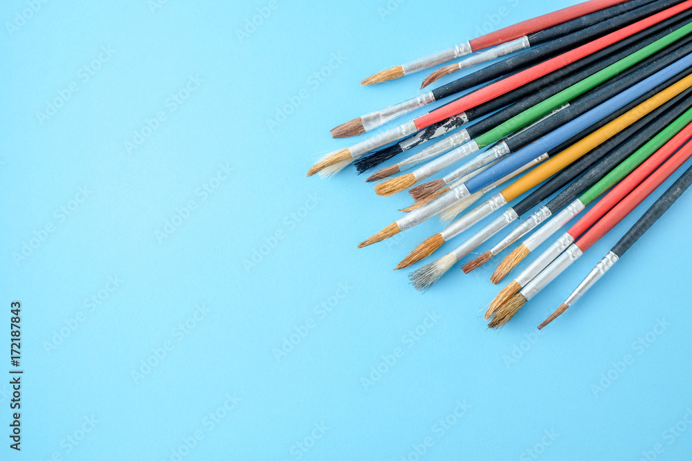 Row of artist paint brushes close up on blue background Row of artist paint brushes close up on blue background