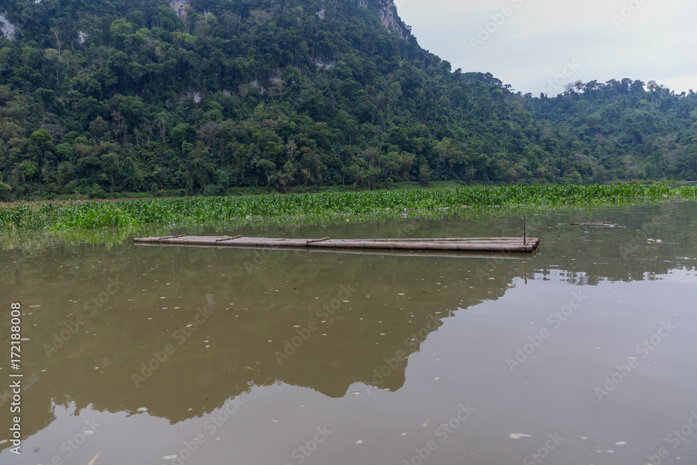 Flat Bamboo raft in Ba Be Lake mountains in distance Flat Bamboo raft in Ba Be Lake mountains in distance
