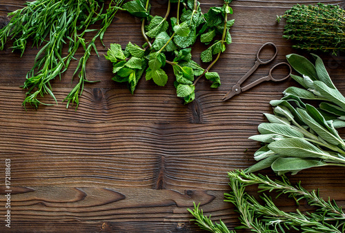 fresh herbs and greenery for spices and cooking on wooden desk background top view mock up