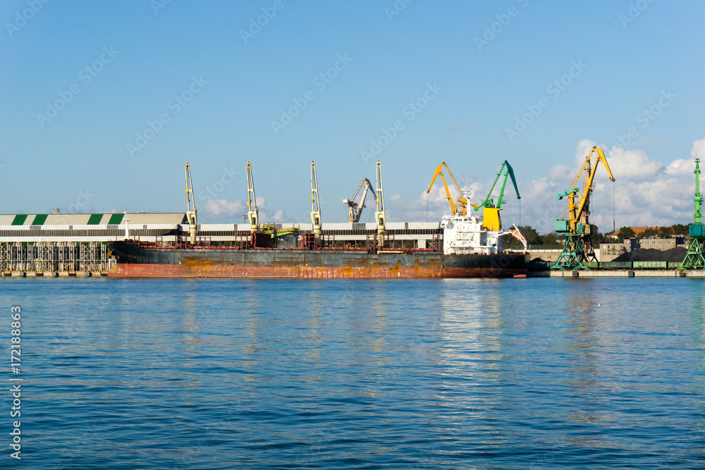 Loading cranes and ship at Baltic sea in sea Port, Klaipeda, Lithuania. Sunset