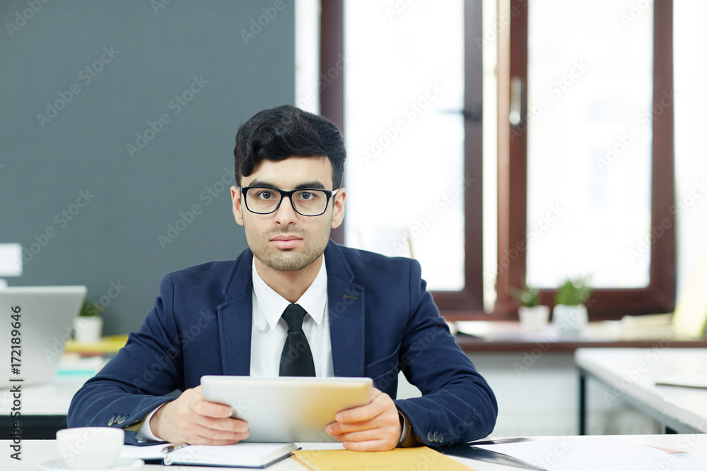 Confident employee with tablet analyzing online data in office Confident employee with tablet analyzing online data in office