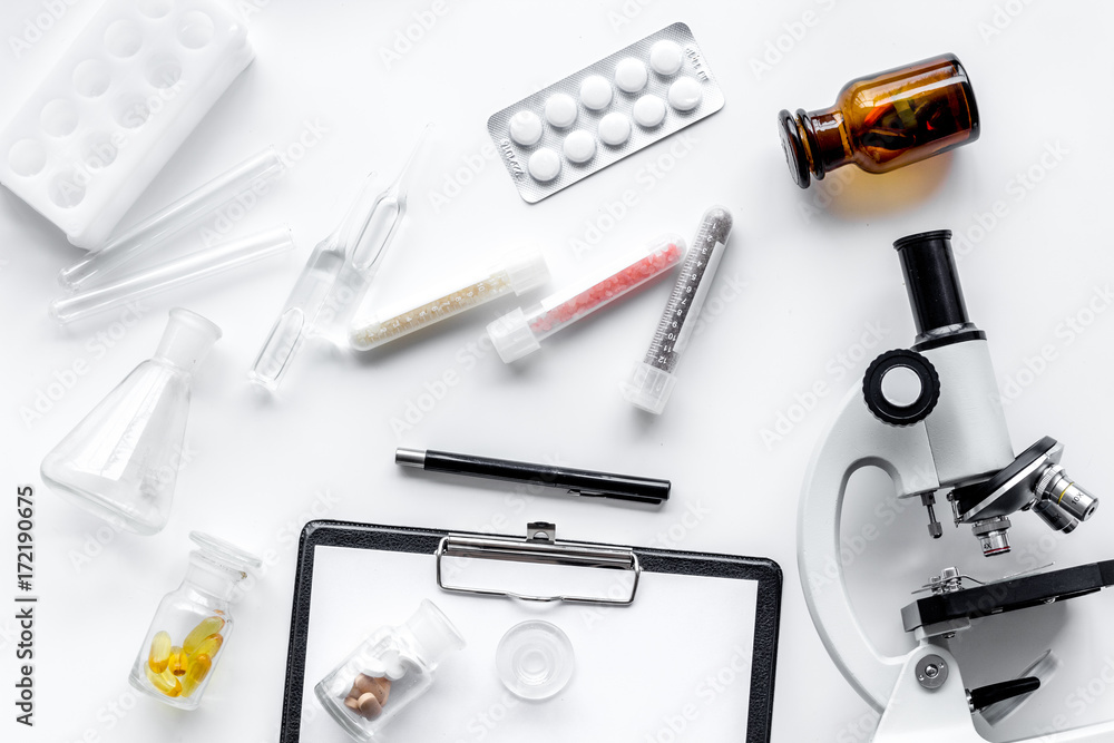Laboratory test. Microscope, pills, test tube on white background top view Laboratory test. Microscope, pills, test tube on white background top view