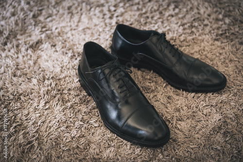 Pair of black leather shoes on beige carpet