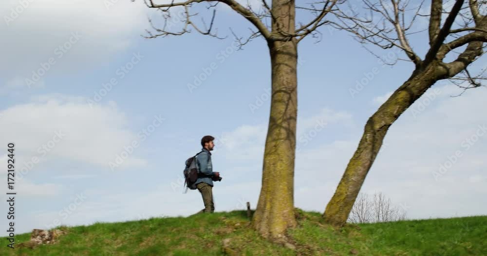 man hiking through woods looking for photos. Following side.Real people Millennial traveller backpacker adult male photographer walking on rural field to shoot photographs in autumn season. 4k video man hiking through woods looking for photos. Following side.Real people Millennial traveller backpacker adult male photographer walking on rural field to shoot photographs in autumn season. 4k video