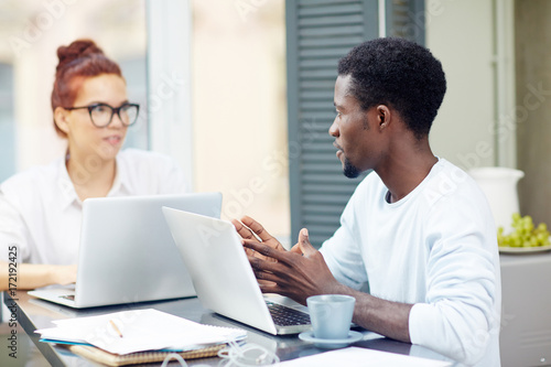 Two home-office workers discussing ideas for new project or making online research