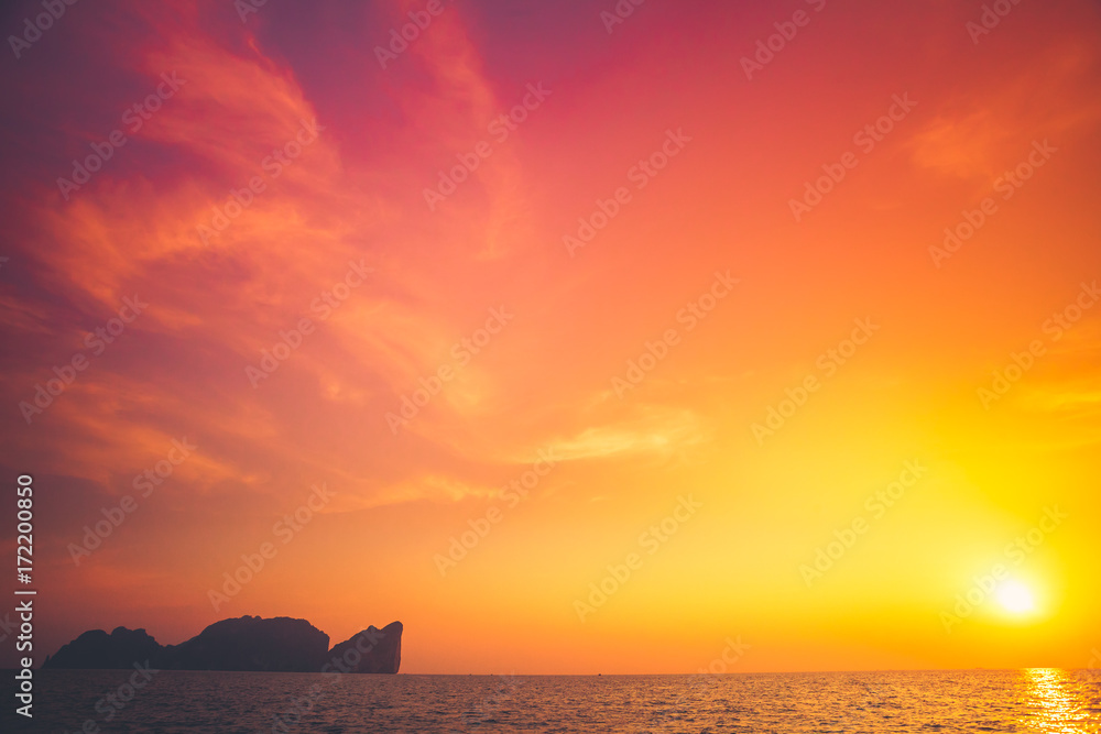Beautiful tropical sunset in Krabi, Thailand. Dramatic and picturesque evening scene. Ocean and colorful orange cloudy sky in the background. Nature landscape. Travel background. Bright purple toning