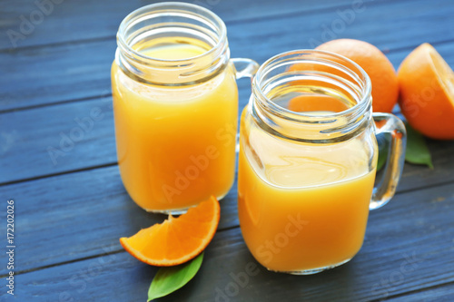 Mason jars with fresh orange juice on table