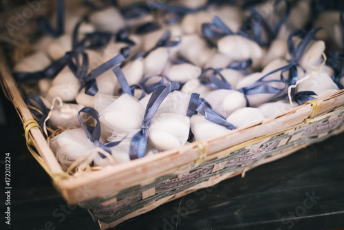 Sugared almonds with blue bows in a wicker basket