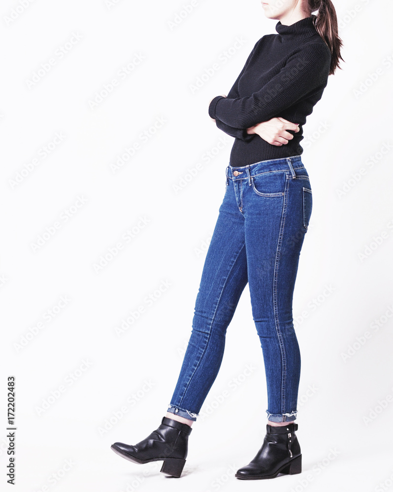 Woman's fall winter fashion outfit on a model with blue vintage skinny jeans,  black turtleneck and black boots isolated on white background. Copy space  Stock Photo | Adobe Stock