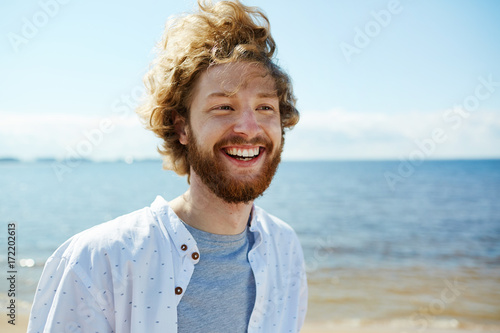 Ecstatic guy expressing happiness and taking pleasure in summer vacation by seaside