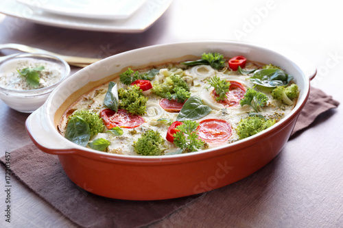 Baking dish with broccoli casserole on table