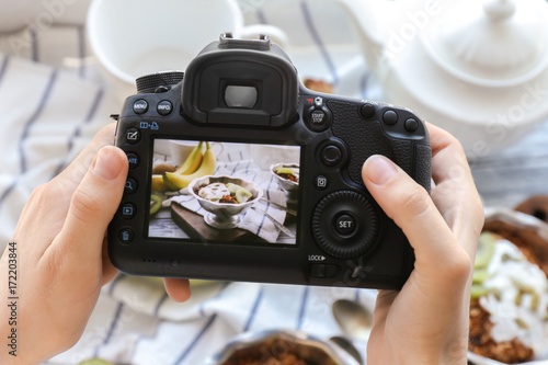 Young woman taking photo of delicious dessert in bowl with professional camera