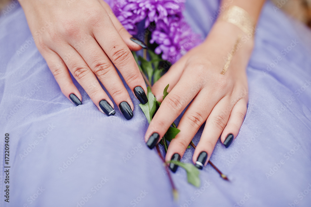 Fototapeta premium Violet aster flowers at hands with black manicure of girl.