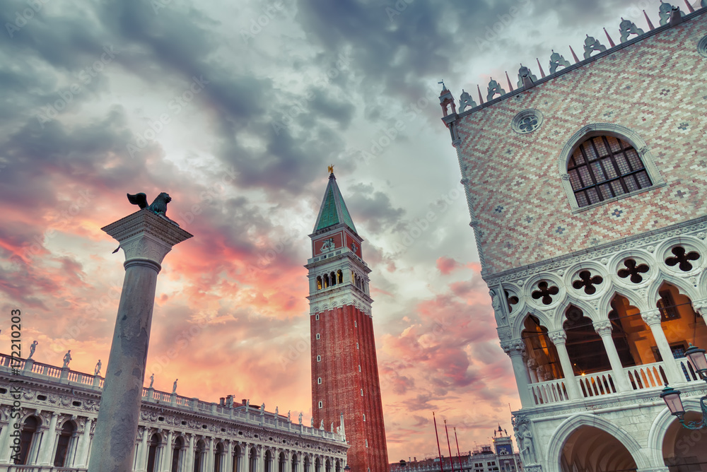 Venice symbol Lion, San Marco Campanile and Doge palace with red dramatic sky during sunset. World famous Venice landmarks