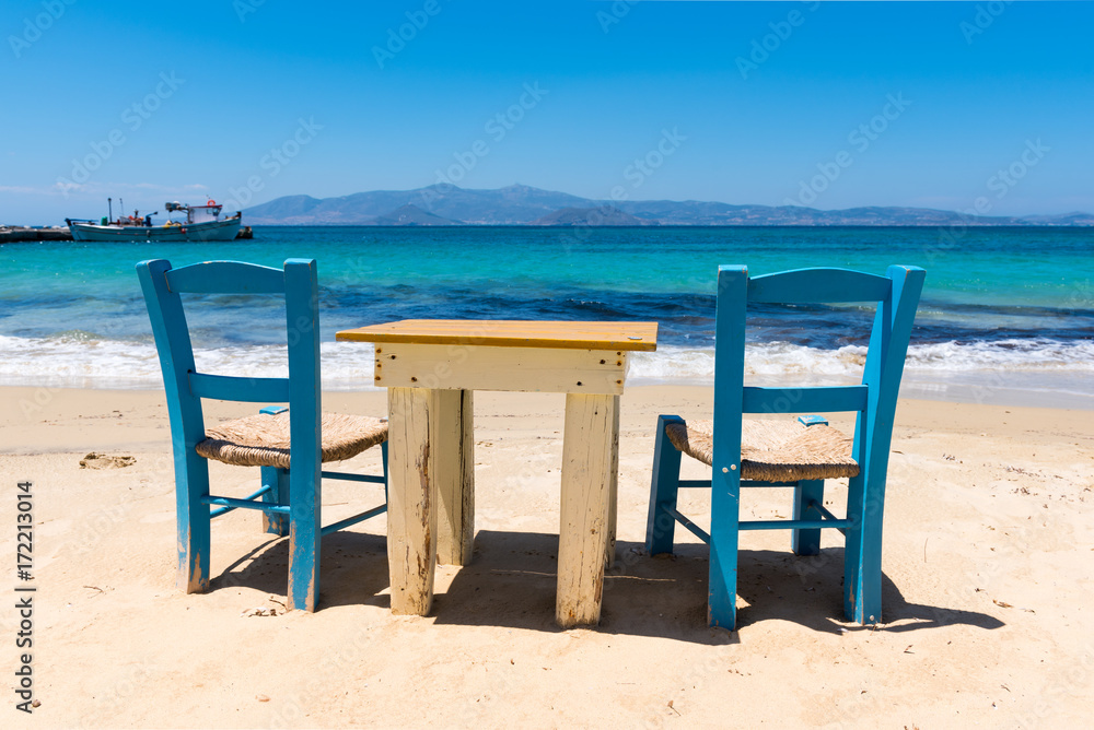 Table with chairs on the beach with beautiful sea view. Agia Anna village on Naxos Island. Greece.