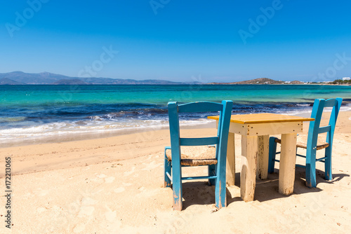 Table with chairs on the beach with beautiful sea view. Agia Anna village on Naxos Island. Greece.