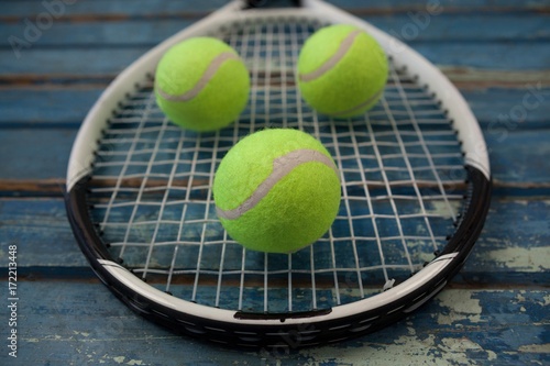 Close up of fluorescent yellow tennis balls on racket over table