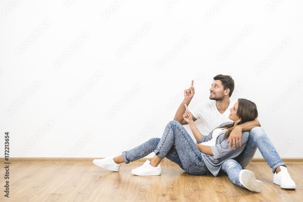 The happy couple sit and gesture on the background of the white wall The happy couple sit and gesture on the background of the white wall