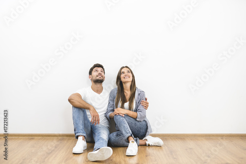 The happy couple sit near the white wall