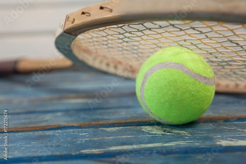 Close up of wooden tennis racket leaning on fluorescent yellow