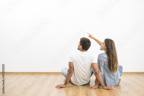 The sitting couple look the empty wall and gesture