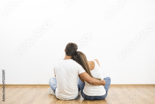 The sitting couple hug on the empty wall background photo