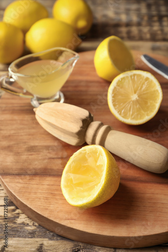 Squeezer and lemons on wooden board