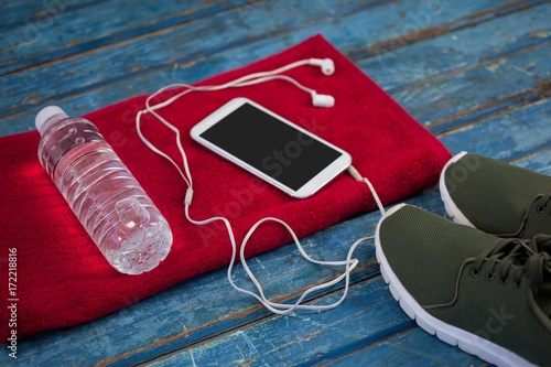 High angle view of water bottle with mobile phone and in-ear