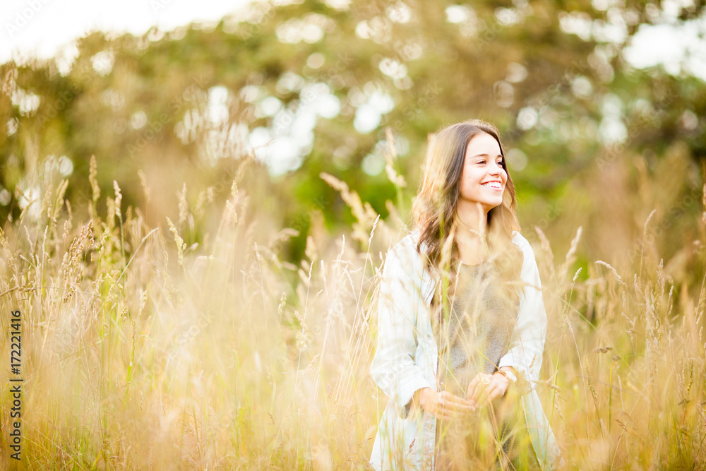Portrait of a smiling girl in a dry grass field and sunset in summer Portrait of a smiling girl in a dry grass field and sunset in summer